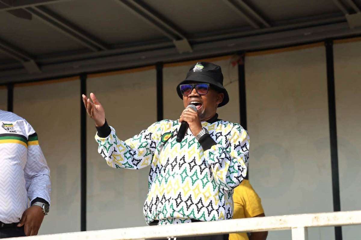 Collen Malatji speaking into a microphone during a community programme.