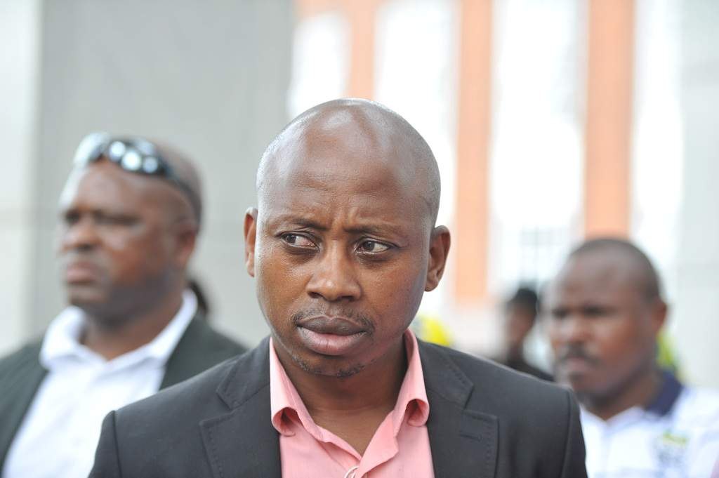 Andile Lungisa in a dark jacket and pink shirt.