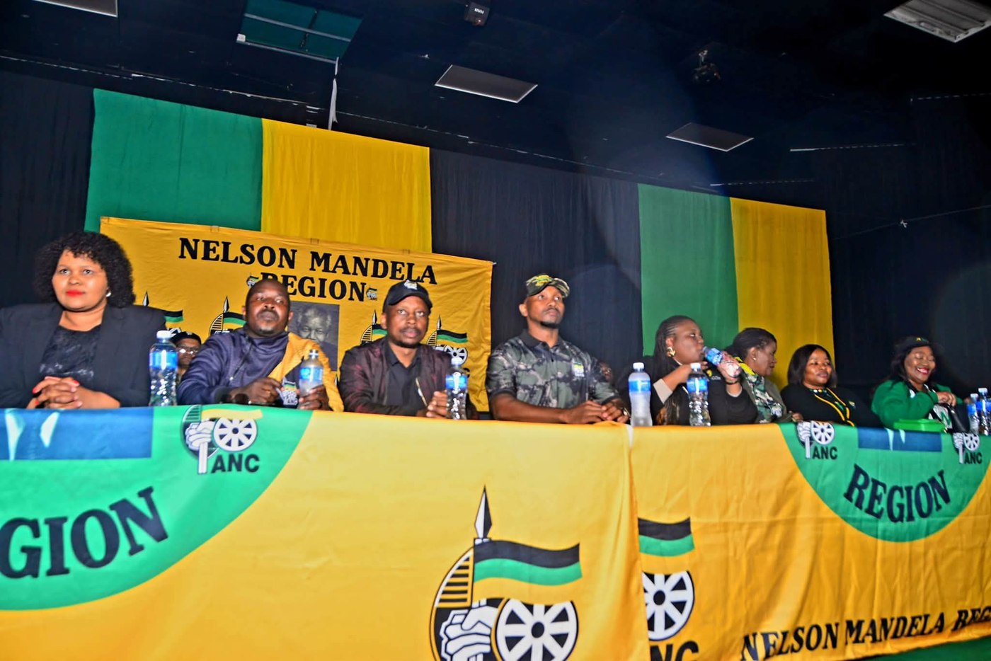 Participants seated behind an ANC-draped platform table beneath a Nelson Mandela Region banner.